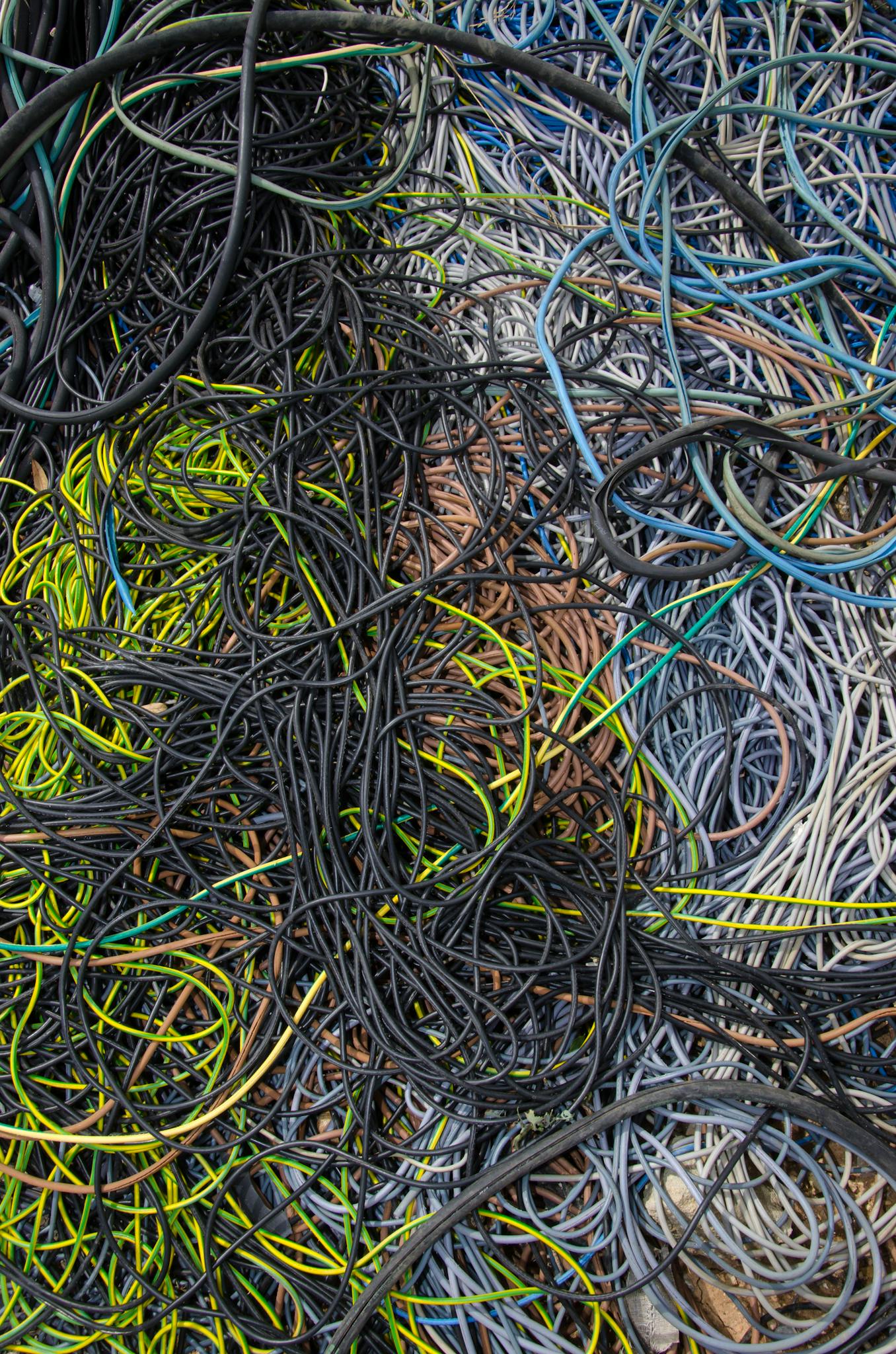 A chaotic tangle of multicolored cables and wires, illustrating complexity and confusion.